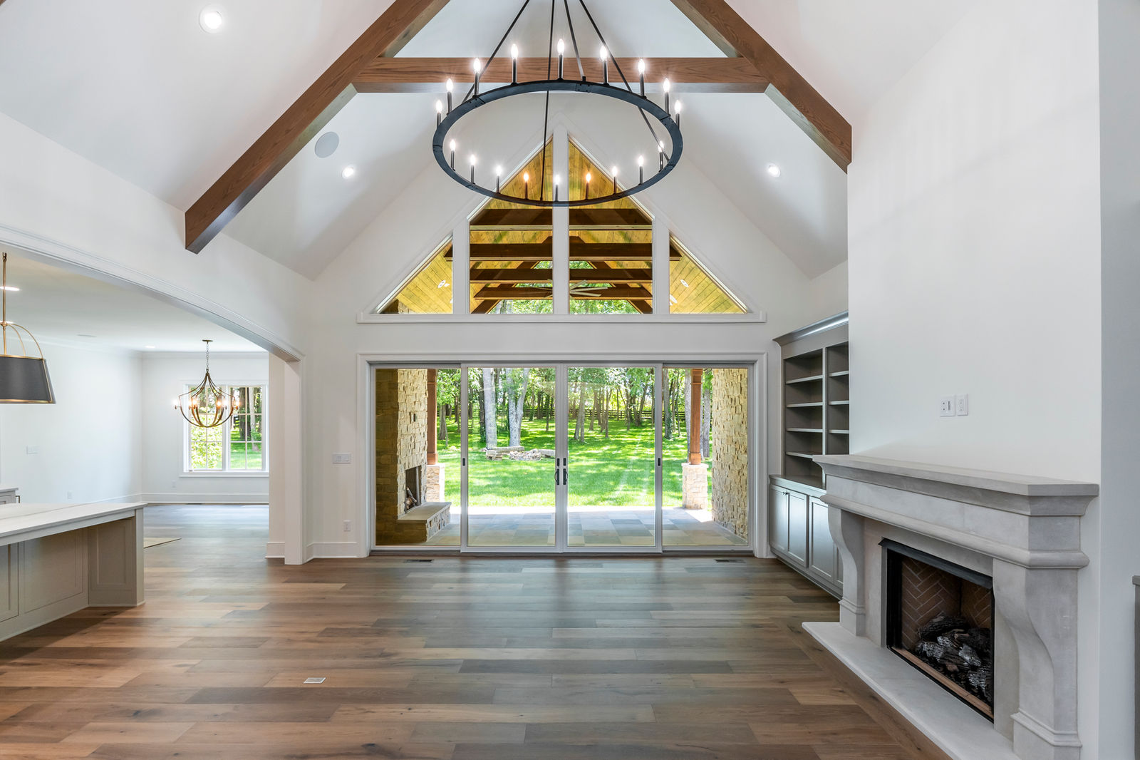 Vaulted living room with timber beams opening to a covered outdoor room