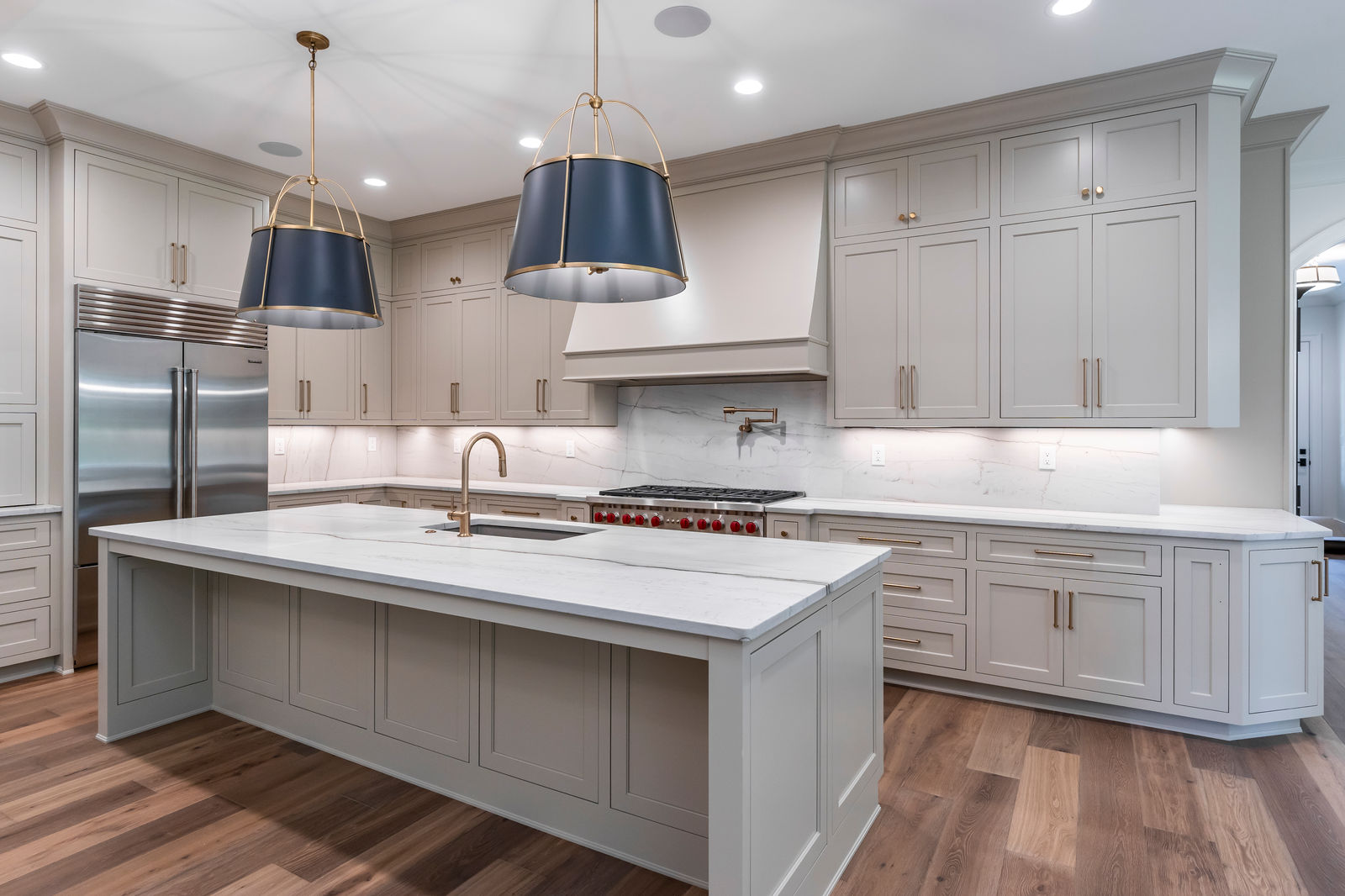 Light kitchen with a marble island, brass fixtures, and paneled cabinets