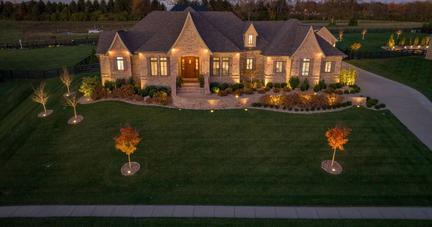 Dusk view of a brick Gale custom home with a lit walk and young trees